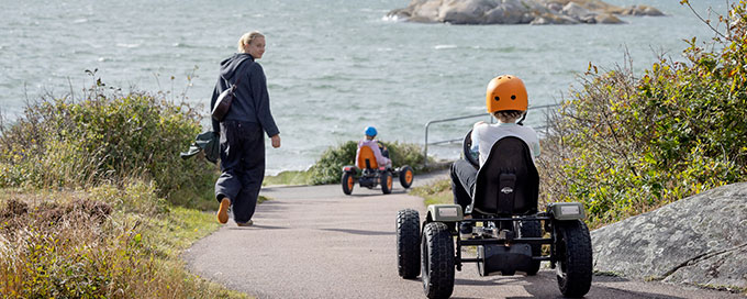 Tv&aring; barn &aring;ker trampbil ner mot havet.
