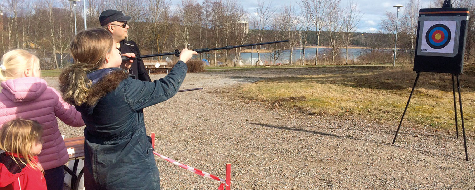 Ett barn skjuter prick med blåsrör utomhus.